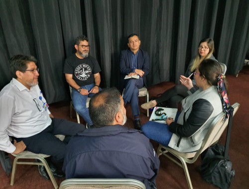 : Mesa de trabajo con representantes de la ONEMI y de la comunidad, siendo capacitados en plan de ayuda para la atención psicológica en situaciones de desastres.